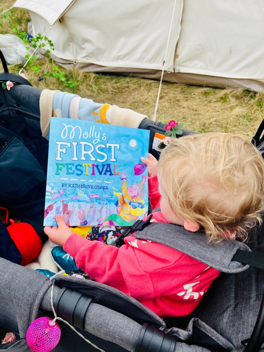 image of baby holding a book which is titled 'molly's first festival' 